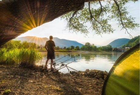Pêcheur au bord d'un lac en train de pêcher à côté de sa tente