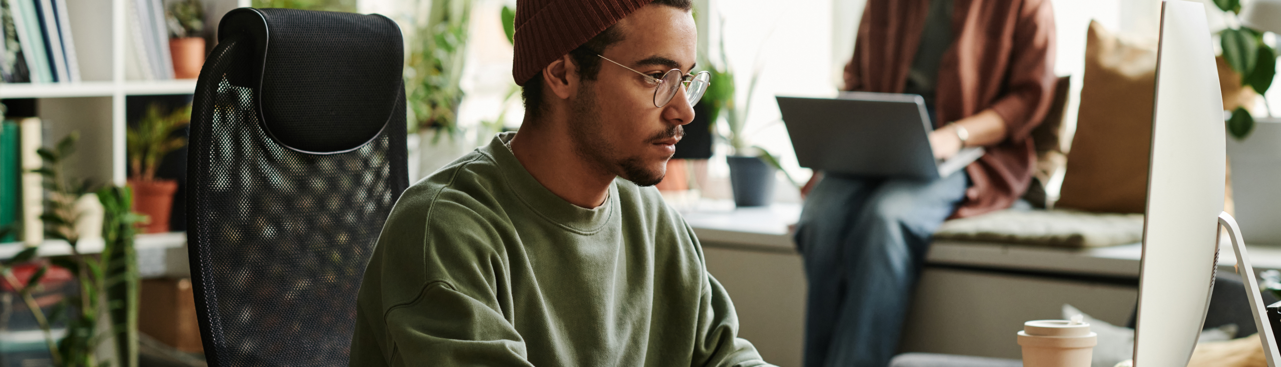 Jeune webdesigner sérieux en tenue décontractée travaillant sur un nouveau site Web sur ordinateur tout en étant assis devant un écran et en tapant