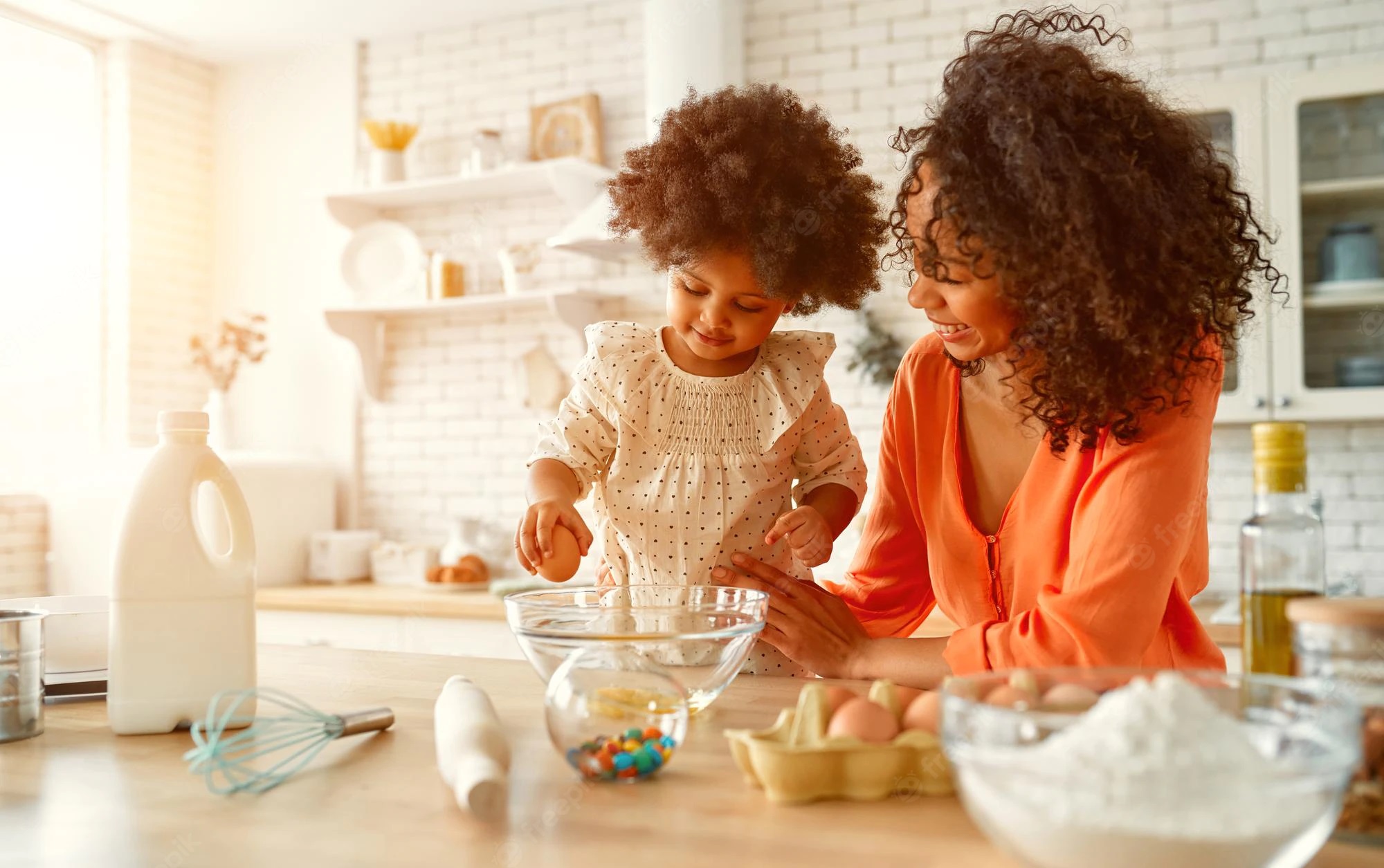 Une femme afro-américaine avec sa petite fille aux cheveux bouclés et duveteux s'amusant à faire des pâtisseries dans la cuisine. Cuisine mère-fille, cuisiner ensemble.